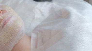 Arka plan bulanık. Kamera hareketi. Bandaj bir kızın yüzü. Güzellik salonu kadın cilt gençleştirme için kozmetik prosedür. Yakın çekim. Sağlık ve güzellik.