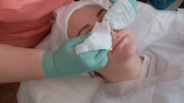 Şevval Özçelik Güzellik maske kalıntıları ıslak mendil yardımıyla üzerinden güzel bir kızın yüzünü temizler. Güzellik salonu kadın cilt gençleştirme için kozmetik prosedür. Yakın çekim.