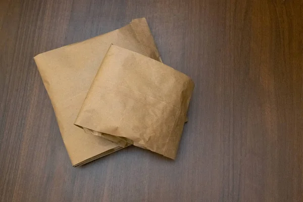 Twee papieren zakken op de tafel met een houten structuur. Walnut achtergrond. Het concept van het gebruik van milieuvriendelijke verpakking. Kopiëren van ruimte. — Stockfoto