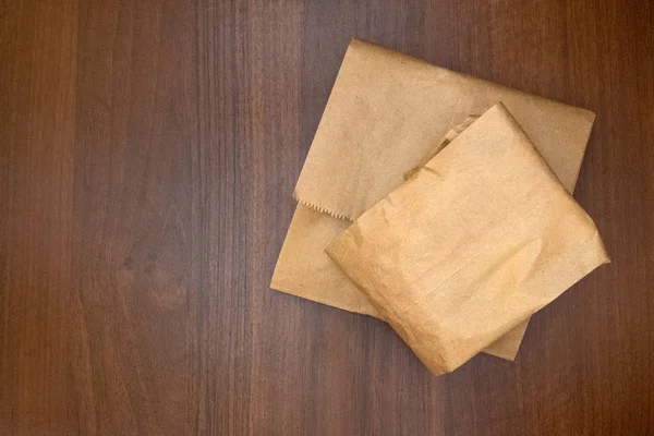 Papieren verpakkingen zakken van voedsel liggen op tafel. De textuur is houten. Walnut achtergrond. Kopieer ruimte. Het concept van het gebruik van milieuvriendelijke verpakking. — Stockfoto