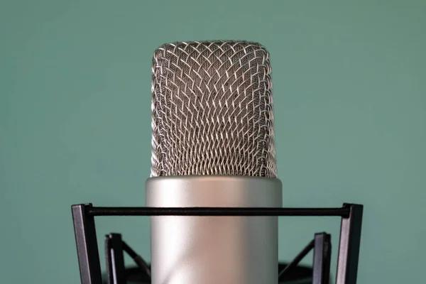 Close-up of a condenser studio microphone with a shock absorber on a blue background. The concept of high-quality professional sound and voice recording. — Stock Photo, Image