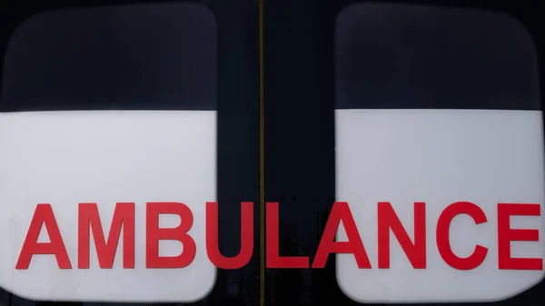 Ambulancia. Inscripción roja en la ventana del coche. Emergencia. Primer plano. Concepto de diseño sobre el tema de la salud y la ayuda a los enfermos . — Foto de Stock