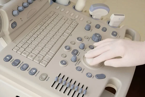 Ultrasound machine closeup. Medical worker makes ultrasound of a pregnant woman. Hand in a white glove on the control panel.