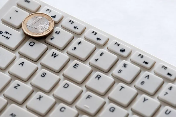 Clavier d'ordinateur et une pièce en euros se rapprochent sur fond blanc. Affaires Internet. Change de devises — Photo