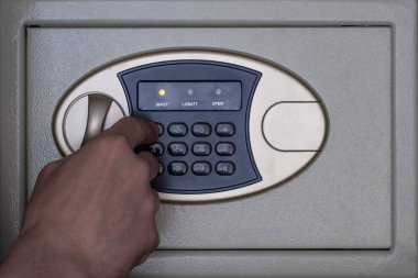 Bir adamın eli bir şifreyle güvenli bir kutuyu açar veya kapatır. Bir banka veya otelde finansal hizmet. Para depolama konsepti.