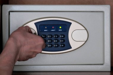 Ofiste ve evde değerli eşyaların ve paranın güvenli bir şekilde saklanması. Yakın çekim erkek eli bir kombinasyon kilidi ile kasayı açar. Banka Kabinesinde işlerin güvenliği