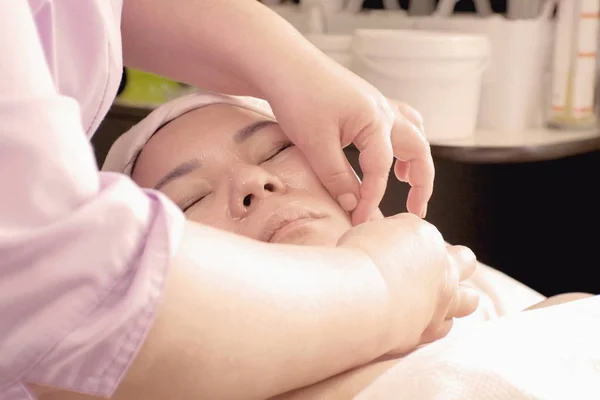 Close-up van vrouwenhanden doen acupressuur Aziatisch meisje in een schoonheidssalon. Procedure voor de gezondheid van de persoon. Cosmetologie en massage — Stockfoto