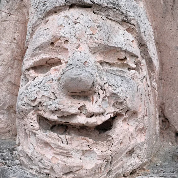 La faccia di un giullare di pietra. Un uomo pietrificato sorridente. La consistenza del guscio rosa roccia. Dettaglio scultoreo. Gioioso concetto emotivo . — Foto Stock