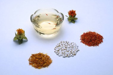 Çiçekli ve safrançiçekleri. Ev bahçesi için tohumlar. Carthamus tinctorius aspir. Beyaz arka planda aspir baharat ve kozmetik yağ.