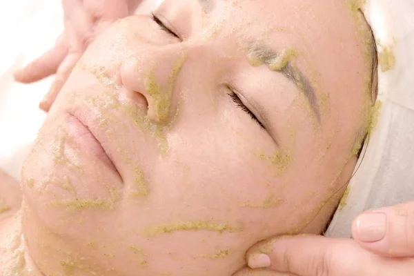 Het meisje in de schoonheidssalon neemt gezichtsbehandelingen. Close-up van een vrouw met een masker van groene algen op haar gezicht. Schoonheid en gezondheid. — Stockfoto