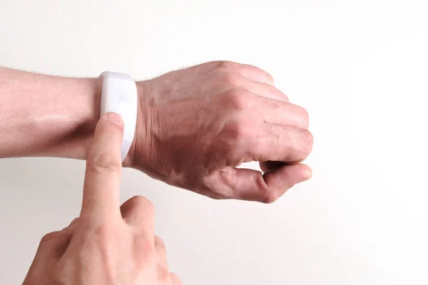 Pulsera blanca en una mano. Un dedo hombre activa, enciende o apaga el gadget moderno. Concepto de tecnología digital, gestión y control de las actividades humanas o comunicaciones inalámbricas de dispositivos de demostración . —  Fotos de Stock