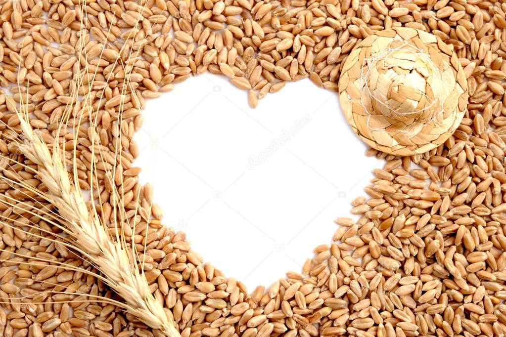 Peasant labor, grain and love. Preparation for a postcard in the form of a heart of wheat. Frame with copy space. Wheat ear and straw hat.