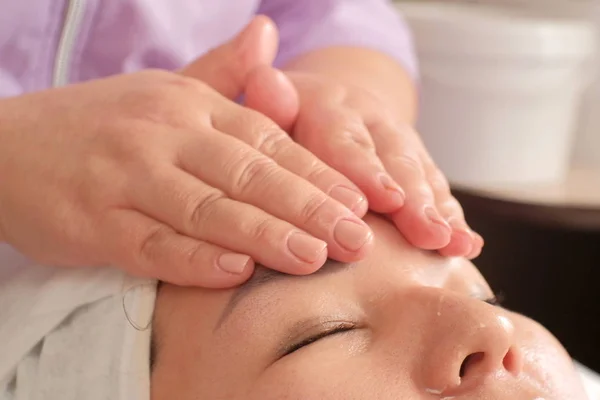 Rughe liscianti sul viso della donna. Primo piano di massaggio sulla fronte femminile. Cura del viso e del corpo nel salone di bellezza . — Foto Stock