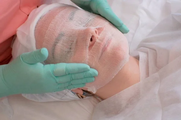 Schoonheidsspecialiste covers gaas vrouw gezicht voor alginaat masker. Vrouw gezicht en handen schoonheidsspecialiste close-up. — Stockfoto