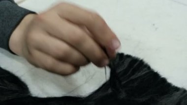 Bir gencin eli keçe ile çalışır. Yünden resim yapmak için iğne. Beyaz kumaş bazında siyah keçe desen doldurma. El yapımı zanaat.