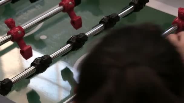 Gioco da tavolo di calcio. Foosball. Primo piano della mano di un bambino che lancia la palla in campo con i giocatori di calcio in nero e rosso. Competizione di squadra e intrattenimento sportivo . — Video Stock