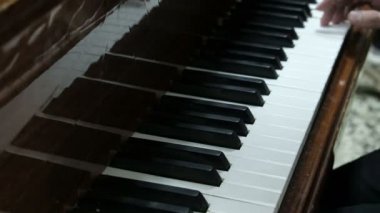 Adam piyano çalıyor. Genç bir adamın elleri bir müzik aletinin beyaz ve siyah tuşlarına basın. Genç bir piyanist bir konser prova.