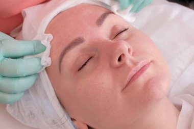 Güzellik uzmanı ıslak mendil bir kadının yüzünü siler. Cildi temizlemek ve nemlendirmek. Güzellik salonunda güzellik ve sağlık.