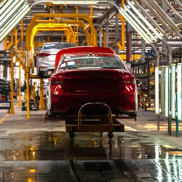 El cuerpo del coche rojo en la línea de producción. Planta de vehículos o taller de reparación de automóviles. Estudio de sintonía automática. Marco cuadrado — Foto de Stock