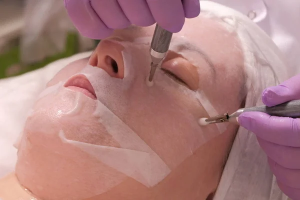 Procedimento do aparelho de cosmetologia. Massagem facial microactual. As mãos de um cosmetologist em luvas rosa alisam dobras com a ajuda de eletrodos. Conceito de rejuvenescimento da pele, saúde e beleza . — Fotografia de Stock