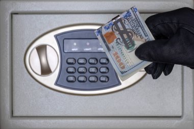 Siyah eldivenli bir hırsız güvenli kapıyı bir şifreyle açar. Evde güvenlik, otel ve ofis konsepti. Değerli eşyaların ve paranın çalınması.