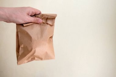 Elinde içindekiler olan kahverengi bir kese kağıdı tutan adam. Kavram Ekolojisi ve doğa koruma. Geri dönüştürülebilir ve bozunabilir ambalaj kullanımı. Beyaz arka plan. Kopyalama alanı.