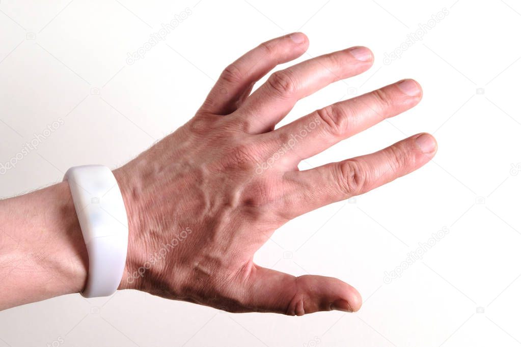 Men's hand with a white bracelet that looks like an electronic watch. Radio-controlled glow and blinking in the dark device pixmob. Gadget for use in mass shows and concerts.