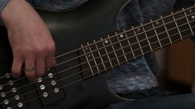 Close. Siyah elektrik bas gitar çalan bir adam. Müzikal performans veya ev konseri.