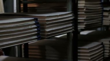 Kahverengi giysiler içinde bir kütüphane ziyaretçibelgeleri ile raflar arasında yürüyor. Eski edebiyatlı kitaprafları. Arşiv odası veya alacakaranlıkta kitap deposu.