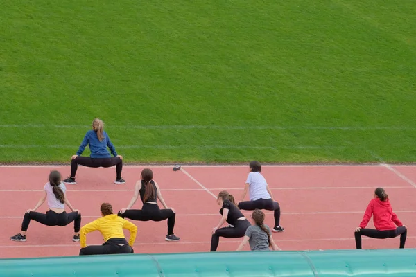 Styrke og stramme bekkenmusklene og lårene. En gruppe unge jenter i fysisk trening på gata. Klasser med turvogngruppe og individuelt . – stockfoto