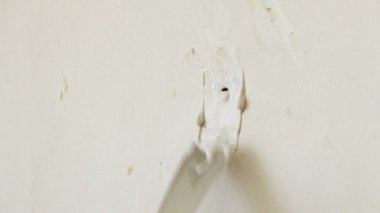Bir spatula ile tamirci erkek el deliği mühürlemek için duvara macun uygular. Modern teknoloji onarım.