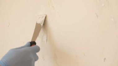 Duvarlar sıva. Spatula ile mavi eldiven bir erkek el beton bir delik için yapıştırın uygular. Modern teknoloji onarımı. Pencereden doğal aydınlatma.