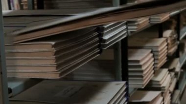 Bir kadın kütüphanede bir kitaplık üzerinde büyük bir kitap veya gazete seti koyar. Bir kütüphanecinin eli yakın. Okula geri dön. Eğitim ve öğretim.