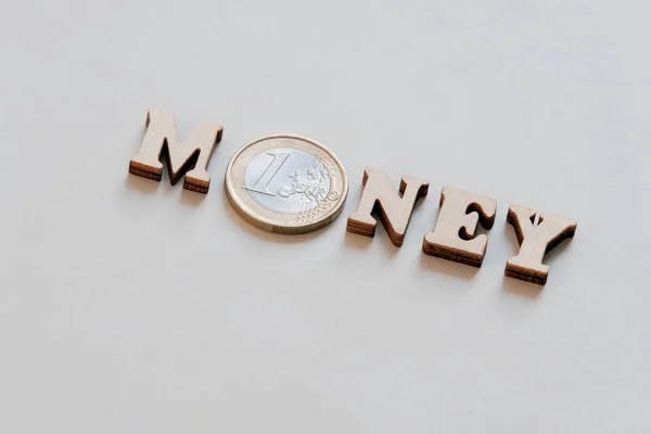 Le mot argent est écrit en lettres de bois et une pièce d'un euro. Texture de fond. Bannière pour l'impression . — Photo