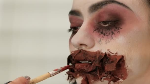 Cadılar Bayramı makyajı. Kanlı ağızlı korkunç bir bayanın görüntüsü. Makyaj sanatçıları el bir fırça ile modelleri dudaklar fırçalar. — Stok video