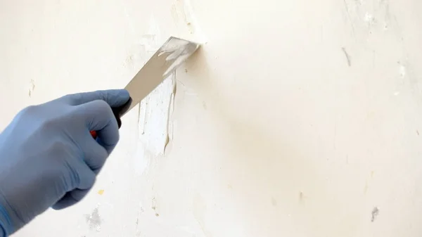 Macun bıçak tamir duvarı ile mavi eldiven el, macun bir tabaka uygulama işlemi, bir spatula ile onarım bitirme çalışması. Kopyalama alanı.