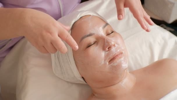 Kosmetikerin Hält Ihre Hände Über Das Gesicht Einer Asiatischen Frau — Stockvideo