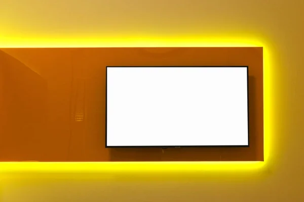 Espaço de cópia branca na tela da TV na parede. O design de interiores de um quarto moderno no estilo de minimalismo e oi-tech. Mock-up. Iluminação com lâmpadas LED amarelas. Modelo. Publicidade em branco . — Fotografia de Stock