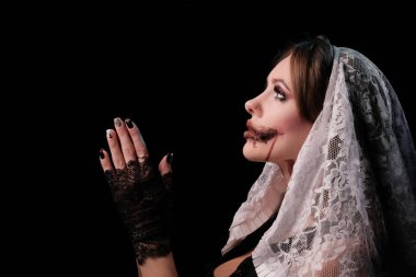 Korkunç bir rahibe kostümü giymiş güzel bir kız sanki bir dua okuyormuş gibi kollarını katladı. Cadılar Bayramı için makyajlı kadın. Bir korku filmi afiş iÃ§in Konsept veya All Saints Day bir parti.