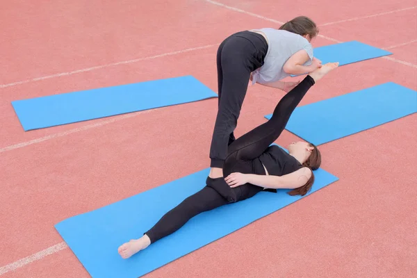 Due ragazze fanno un etude ginnico. Esercizio in un paio di stretching dei muscoli delle gambe. Gli studenti praticano sport all'aria aperta. Ginnastica . — Foto Stock