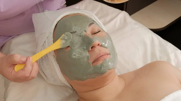 L'estetista applica una maschera di alginato grigio agli occhi di una ragazza cliente. Donna asiatica di mezza età in un salone di bellezza su una procedura ringiovanente. Primo piano di un volto femminile. Stile di vita, salute e bellezza — Foto Stock