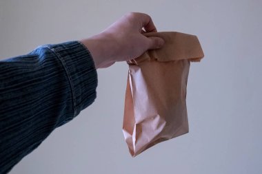Erkek el ileri bilinmeyen içeriği ile bir kağıt torba uzanır. Gıdanın ekolojik ambalajı kavramı, plastik kullanımının reddi, çevre koruma, hammadde lerin geri dönüşümü