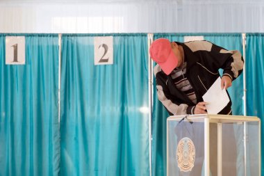 Qazaqstan, 9 Haziran 2019, seçimler, oylama, oylama salonunda kırmızı kapağın içinde bulunan bir adam, oylamayı Kazakistan amblemi ile şeffaf bir kutuya koyar. El yakın çekim. Boşluk Kopyala.