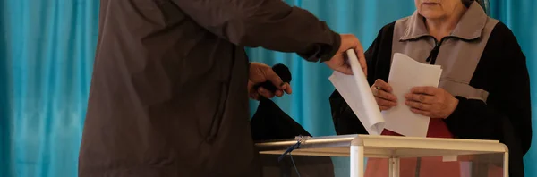 Polling station. Nationwide voting, elections. Elderly man and woman in plain clothes dipping ballots in a transparent box. Panoramic framing for banner. Copy space. — Stock Photo, Image