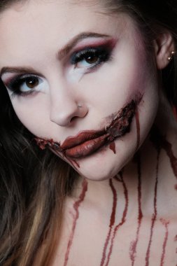 Cadılar Bayramı tatili için makyaj ile seksi güzel bir kız Portresi. Kanlı ağız ve boynunda lekeler var. Close.