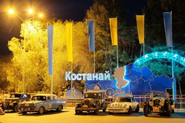 Kazakistan, Kostanay, 19-06-19, Paris'e Park retro otomobil ralliPekin. Gece. Kasaba meydanında eski arabalar. Şehrin Kiril adı üzerine yazıt: Kostanay.