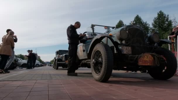 Kazakhstan, Kostanay, 2019-06-20, Rally Peking to Paris. Participant of the rally on the car Chrysler 70 Roadster 1927 release. A man from the attendants records the start time from the town square. — Stock Video