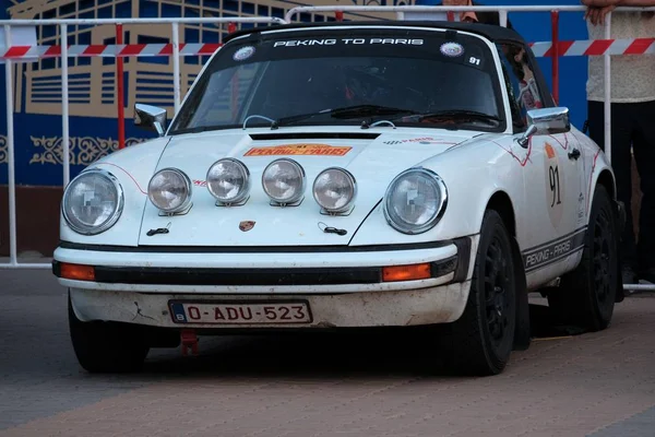 Cazaquistão, Kostanay, 2019-06-20, The 7th Peking to Paris Rally Motor Challenge. Um carro branco retro Porsche está estacionado perto de uma cerca na praça da cidade . — Fotografia de Stock