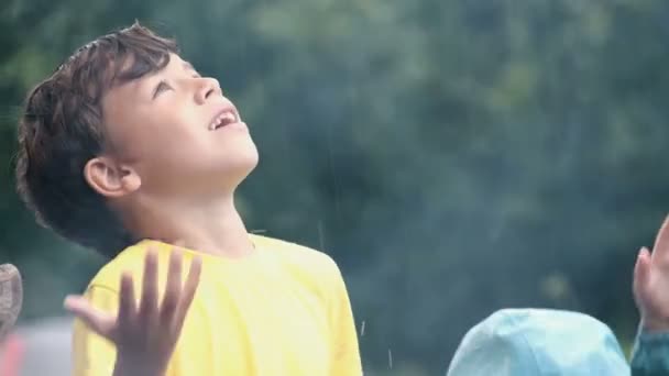 Szczęśliwy chłopiec w żółtym T-shirt łapie krople deszczu na naturę. Dym z ognia na pikniku. Wycieczka, turystyka i rodzinne wakacje. Aktywny styl życia. — Wideo stockowe