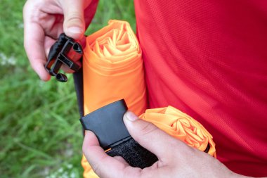 Close. Erkek elleri, kumaş bantları, çizgileri, kemerleri bağlamak için yarı otomatik bir bağlantı cihazını bağlar veya sabitler. Fastex turuncu şişme kanepe Lamzac üzerinde.